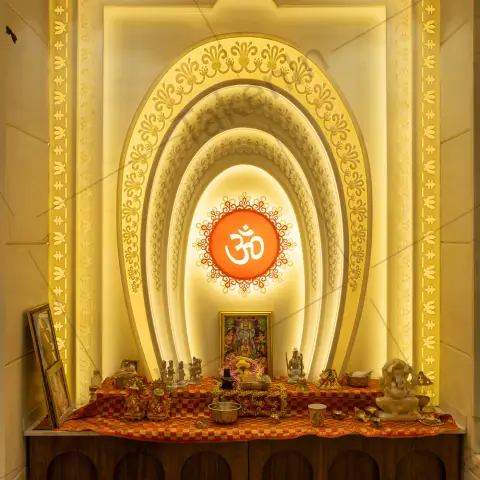 A backlit multi-tier arched pooja mandir with gold trim mouldings, an illuminated Om medallion