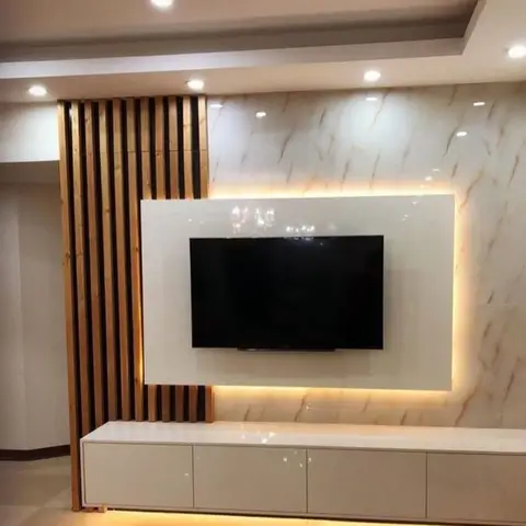 A backlit TV feature wall with gold-veined marble cladding, a vertical wood-slat partition screen, and a glossy white floating console.