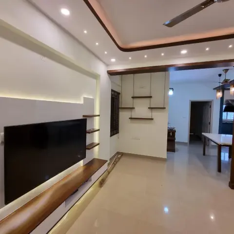 A backlit white TV panel with a live-edge solid wood ledge running beneath the screen and small floating wood shelves at its edge