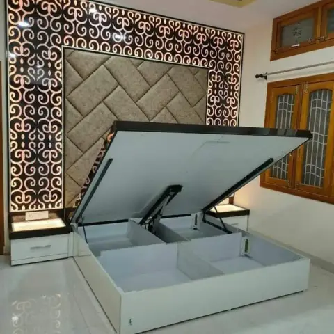 A bedroom showing a white hydraulic storage bed lifted open to reveal under-bed storage compartments