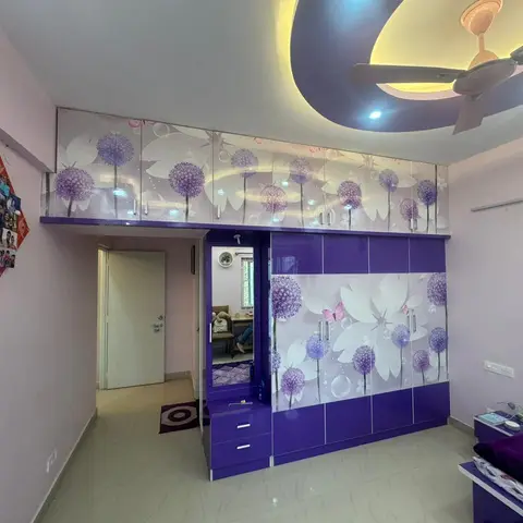 A bedroom with a bold purple wardrobe and loft unit featuring a white dandelion-flower digital print, a built-in mirror console