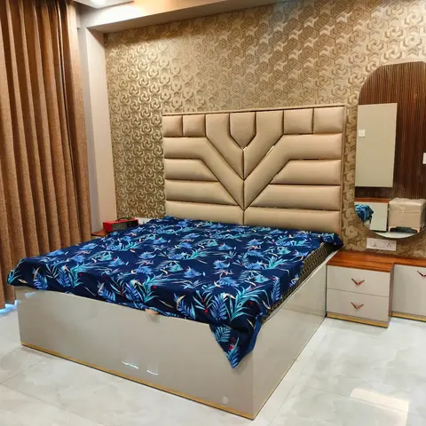 A bedroom with a channel-tufted cream headboard against geometric gold wallpaper, an upholstered storage bed base