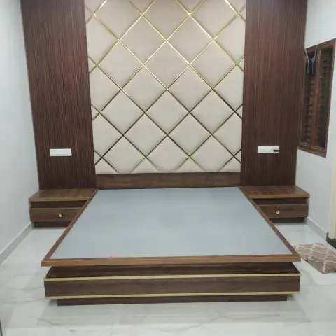 A bedroom with a diamond-tufted cream and gold headboard wall flanked by fluted wood panelling, and a wood platform bed with floating nightstands