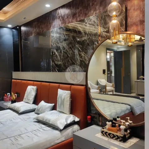 A bedroom with a rust leather channel-tufted headboard, a bookmatched dark marble feature wall