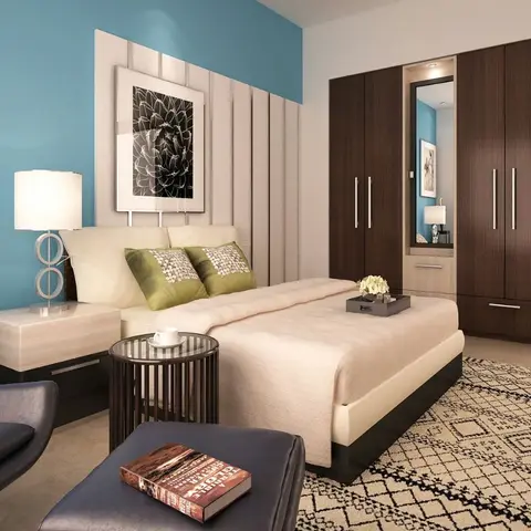 A bedroom with a teal accent wall, cream tufted headboard, dark wood wardrobe with mirror insert