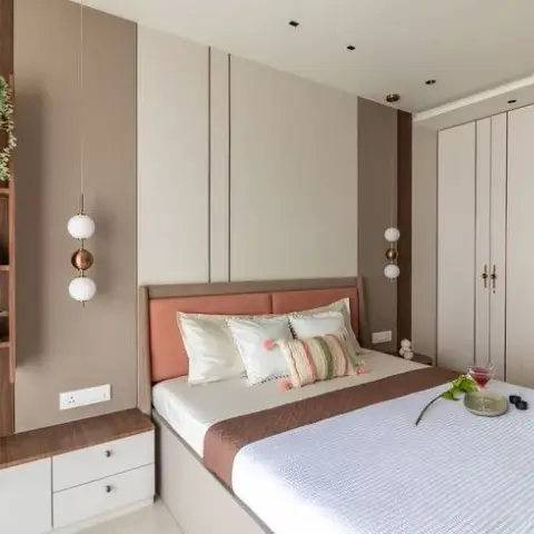 A bedroom with a terracotta upholstered headboard against taupe wall panelling, globe pendant lights