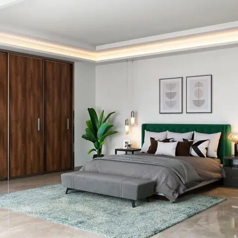 A bedroom with a tufted emerald-green velvet bed, a walnut sliding wardrobe, twin bedside pendant lights, and a cove-lit ceiling.