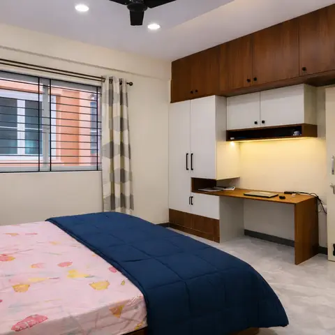 A bedroom with a two-tone wood-and-white wardrobe wall built around an integrated study desk with under-shelf lighting