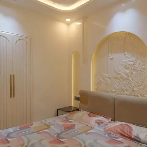 A bedroom with an arched, backlit sculptural relief wall panel of birds and tropical foliage behind the headboard