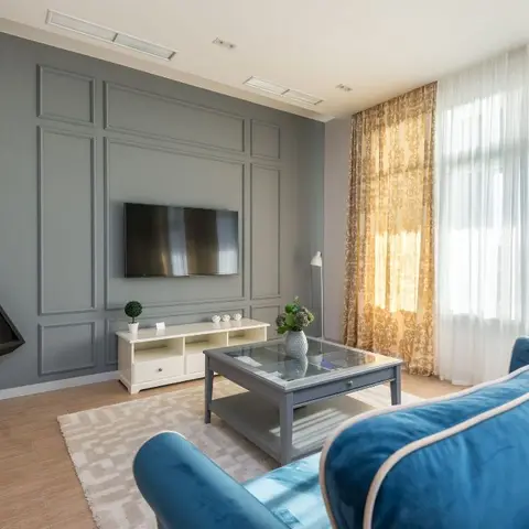 A blue velvet sofa and glass-top coffee table sit before a panelled slate-grey feature wall with a wall-mounted TV and a black modern fireplace