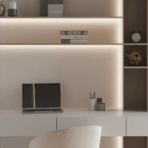 A built-in study desk with backlit open shelving and a laptop set against a beige panelled wall.