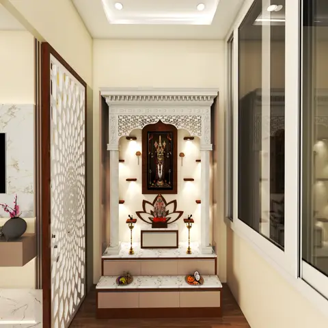 A carved white pooja mandap unit with an arched niche housing a deity idol, marble seating platform, and storage drawers below, beside a jaali screen door