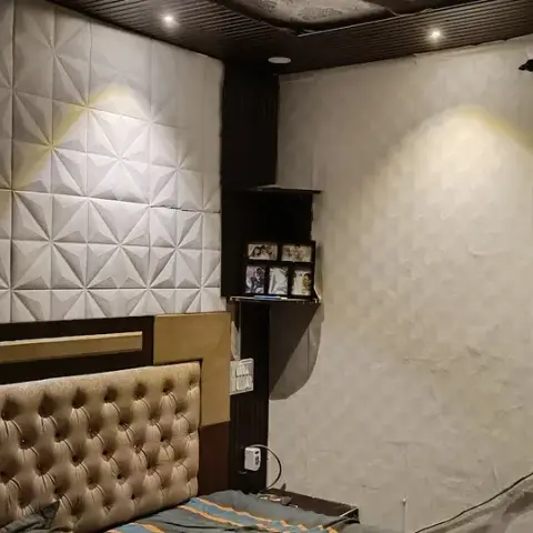 A channel-tufted fabric headboard bed against a white 3D-textured geometric wall panel, under a dark wood slatted ceiling
