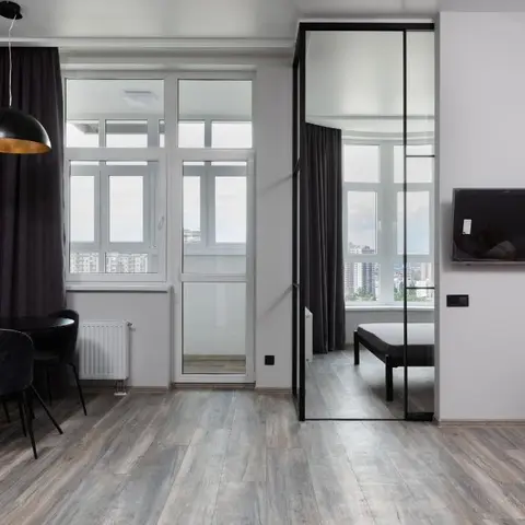 A compact dining nook with a black round table and velvet chairs under a dome pendant light