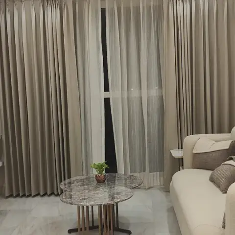 A compact living room with a geometric-textured wallpaper wall and styled floating shelf, floor-length curtains, a cream boucle sofa