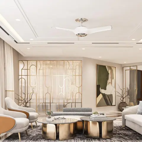 A cream living room with camel-and-grey armchairs, a houndstooth sofa, and gilded round coffee tables set before a gold Art Deco-style jaali partition screen.