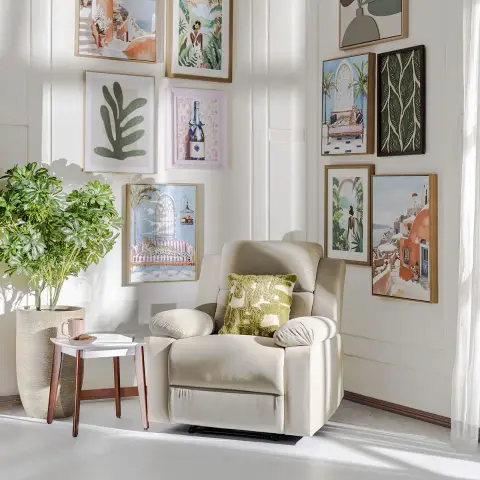 A cream recliner armchair with an olive cushion sits in a panel-moulded corner beneath a dense gallery wall of framed art.
