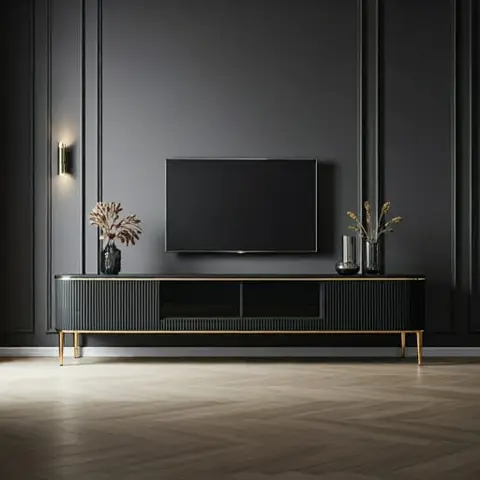 A dark charcoal panel-moulding wall with a wall-mounted TV over a fluted wood console with brass trim and tapered legs, on a herringbone wood floor.