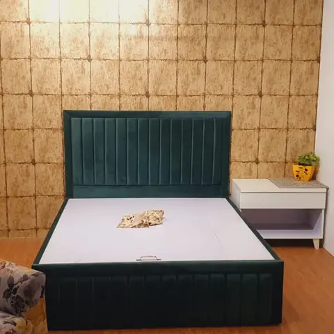 A deep-green channel-tufted velvet bed against a gold quilted-texture accent wall, with a floral wingback armchair and beaded cushion in the foreground.