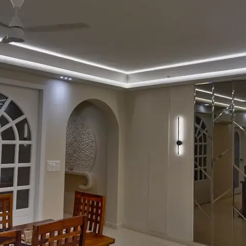 A dining area with arched glass-paneled French doors, a floor-to-ceiling mirrored wall, cove ceiling lighting