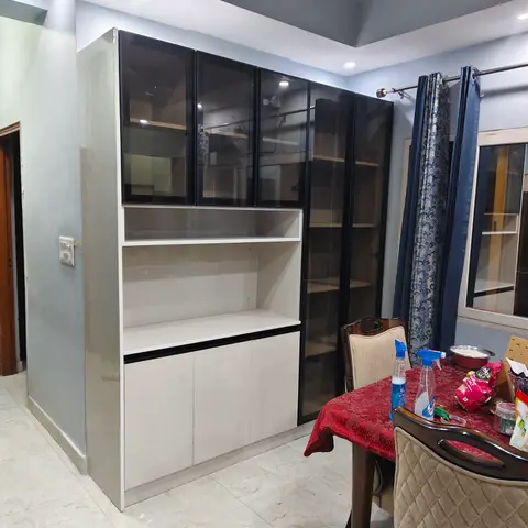A dining corner with a tall black-glass-front crockery unit with an open display shelf