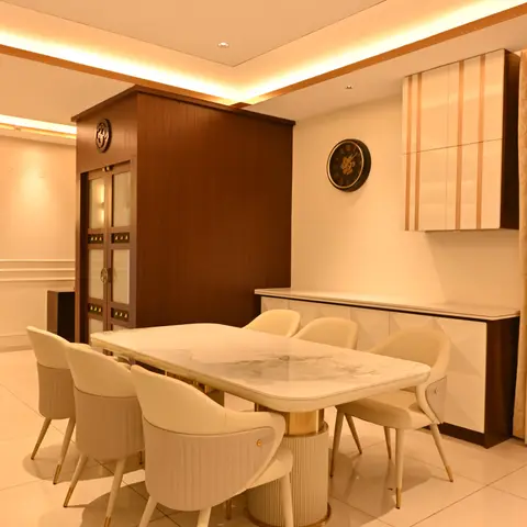 A dining room with a marble-top table on a fluted brass-trimmed base, cream leather dining chairs