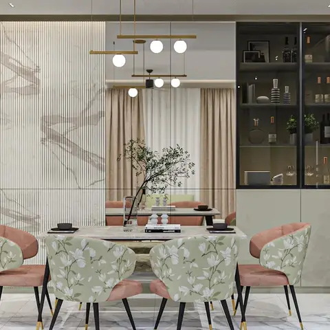 A dining table with pink and floral-print chairs set before a fluted marble feature wall and a glass-front display cabinet styled with bottles and decor