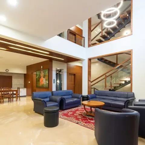 A double-height living lounge with navy leather sofas around a red Persian-style rug