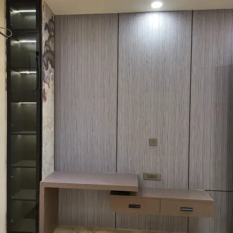 A floating TV console with drawer fronts against a vertical fluted panelling wall, beside a tall glass-front display cabinet with shelf lighting.