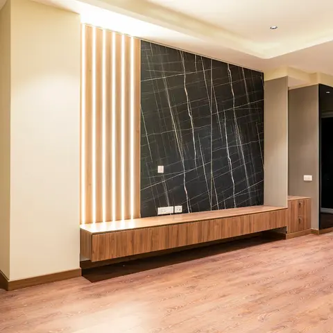 A floating walnut TV console beneath a black-and-gold book-matched marble feature wall, framed by vertical LED strip lighting