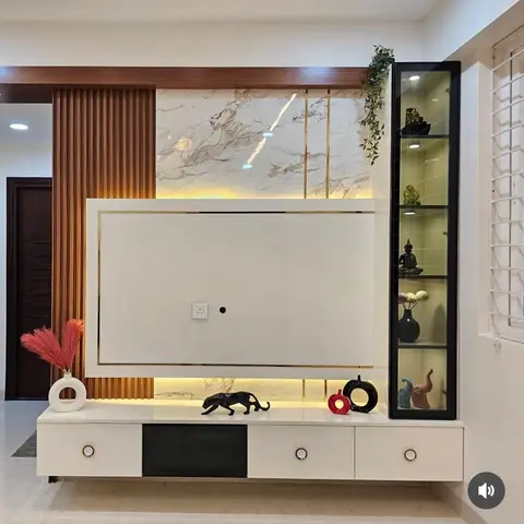 A floating white-and-gold TV console beneath a marble feature panel, flanked by a wood-fluted wall and a black-framed glass curio cabinet styled with figurines.
