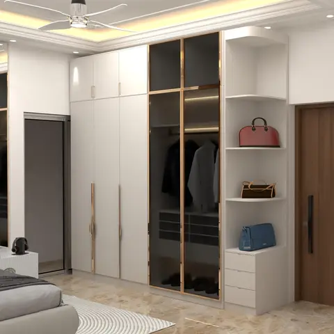 A floor-to-ceiling white gloss wardrobe with bronze-trimmed glass shutters and an open corner shelf styled with handbags