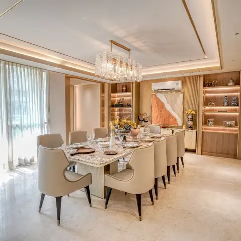 A formal dining room with a long marble-top table seating ten in taupe leather chairs, a linear crystal chandelier