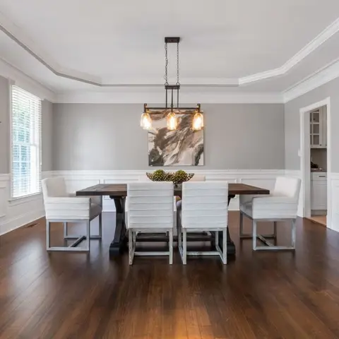 A formal dining room with dark wainscot panelling, a tray ceiling with crown moulding