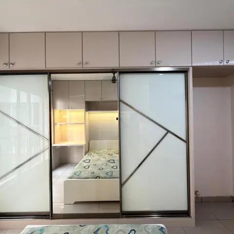 A full-height mirrored sliding wardrobe reflects a single bed with a heart-print quilt and a built-in study nook with cove lighting.