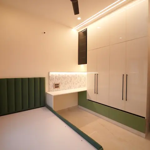 A green fluted upholstered bed base faces a floor-to-ceiling glossy white wardrobe with a green kick panel