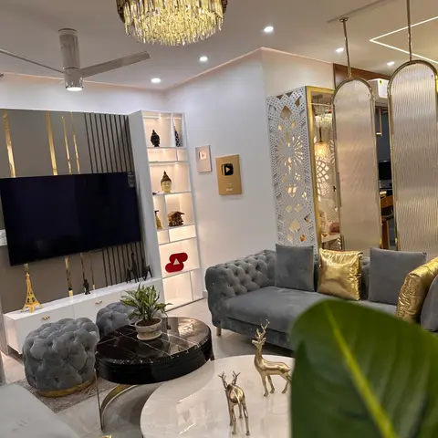A grey tufted velvet sofa with gold cushions sits beneath a tiered gold ring chandelier