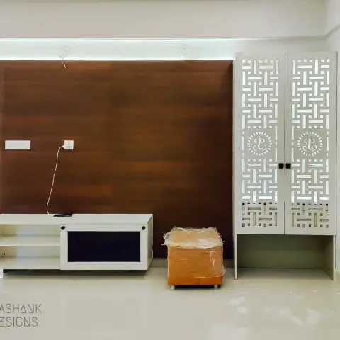 A just-handed-over living room with a walnut-laminate TV back panel lit by a ceiling cove, a low white console below it