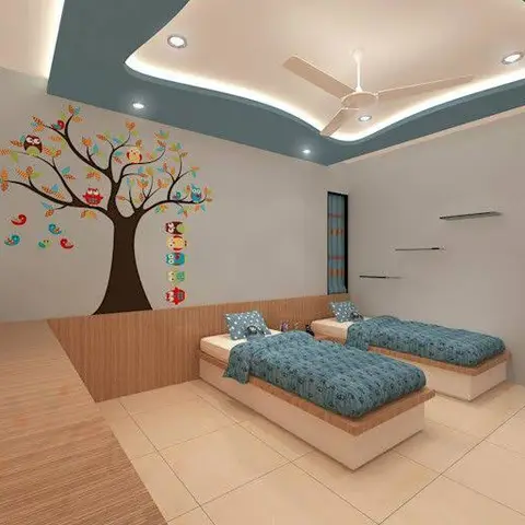 A kids' bedroom with twin built-in platform beds in blue bedding, beneath a curved two-tone pop ceiling, and an owl-and-tree wall decal mural.