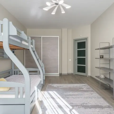 A kids' room with a grey wooden bunk bed holding a large teddy bear, a sliding-door wardrobe, open metal display shelving with toys and flowers
