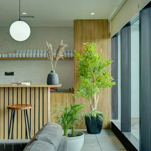 A living-kitchenette nook with a fluted-wood breakfast bar, speckled terrazzo-look backsplash, a globe pendant light