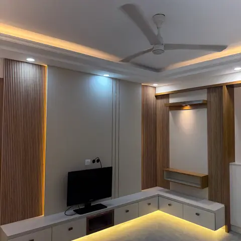 A living room corner with an L-shaped floating TV console under fluted wood wall panelling niches