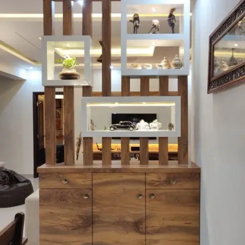 A living room entrance divider made of vertical wood slats with backlit display niches styled with figurines and a model car