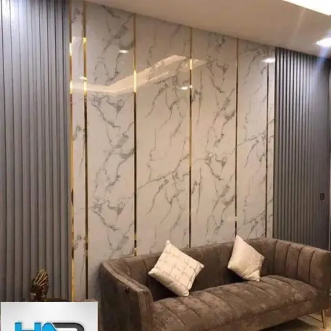 A living room feature wall of book-matched marble panels with brass inlay strips flanked by grey fluted panelling