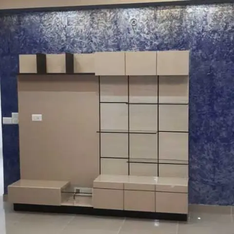 A living room TV unit in beige laminate against a deep blue textured accent wall, with an open doorway to a balcony.