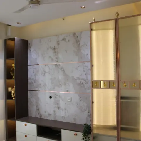 A living room TV wall clad in book-matched marble with rose-gold trim strips, a low TV console with rose-gold handles