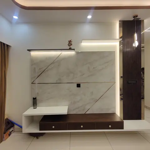 A living room TV wall in backlit marble-effect stone with inlaid copper geometric lines, a floating dark-wood console with drawers