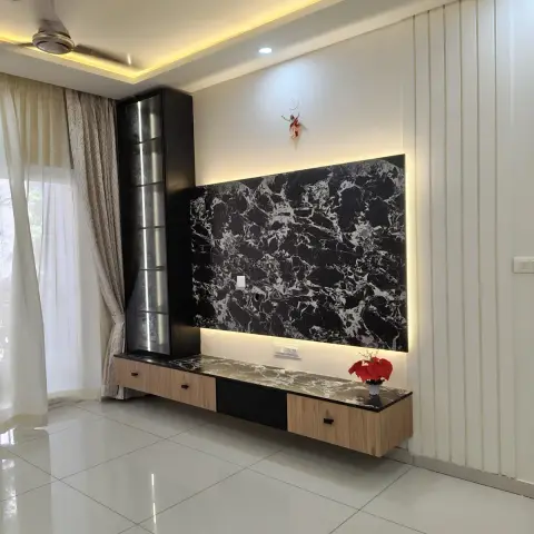 A living room TV wall with a backlit black-and-white marble slab panel above a floating wood-and-black TV console, flanked by fluted white wall panelling.