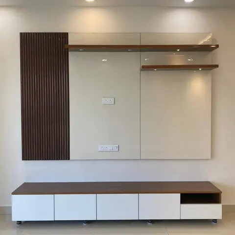 A living room TV wall with a dark walnut fluted panel accent beside a glossy cream backsplash and floating wood shelves