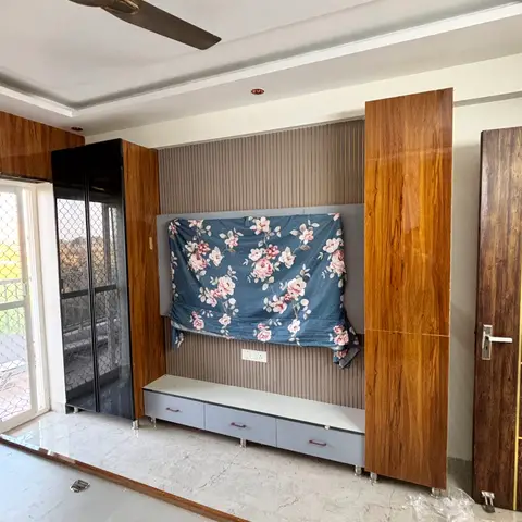 A living room TV wall with a grey fluted panel insert flanked by wood-grain laminate panelling, a low grey TV console with drawers